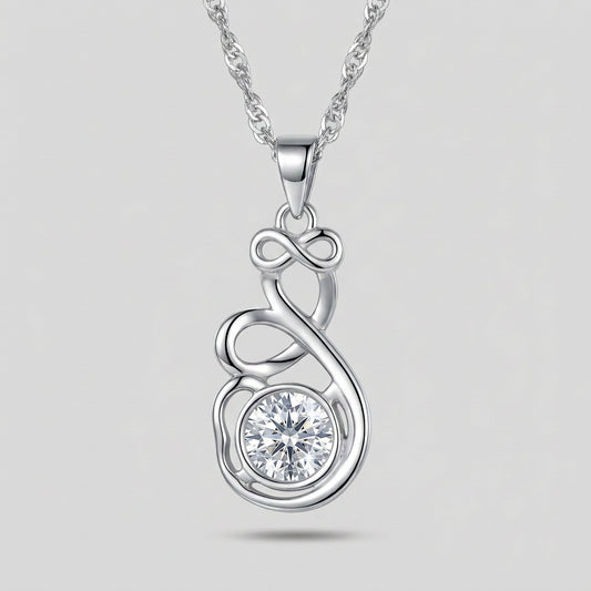 A silver-toned necklace with a pendant featuring an infinity symbol and a clear faceted gemstone, displayed on a dark textured surface with a folded navy blue fabric background.