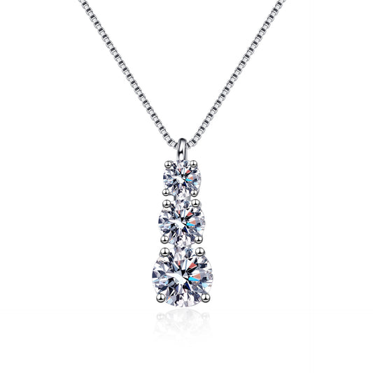 A silver-toned necklace with a three-stone pear-cut diamond pendant, displayed on a clean white background with a subtle reflection.