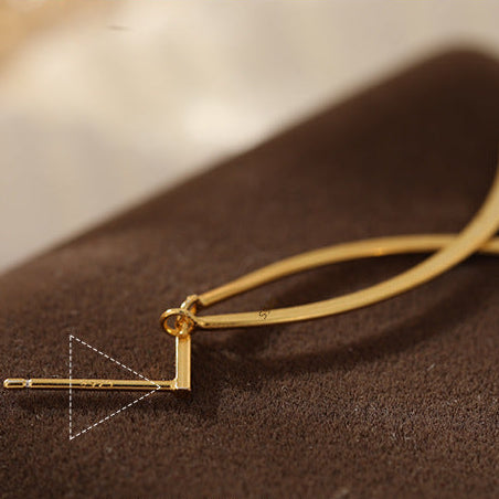 Gold necklace with a geometric pendant on a brown surface