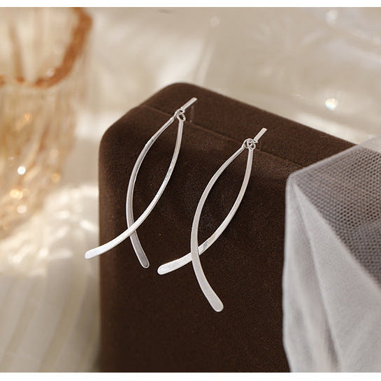 Silver earrings on a brown stand with a soft focus background